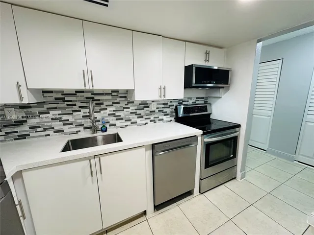 a kitchen with granite countertop a sink stove and microwave