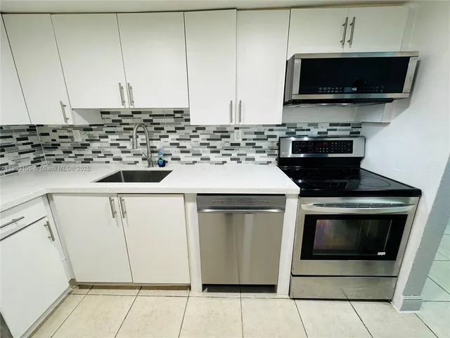 a kitchen with granite countertop a stove top oven microwave and cabinets