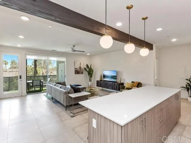 a living room with couches and kitchen view with wooden floor