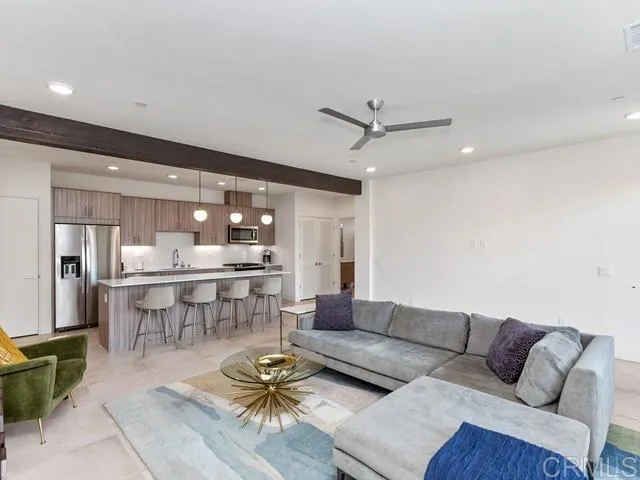 a living room with furniture a rug and kitchen view