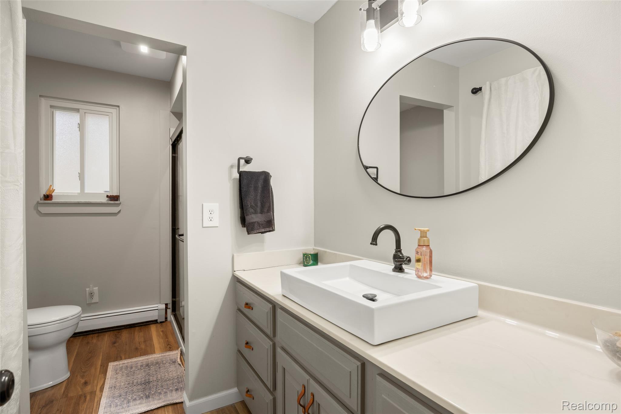 8639 Stone Road Algonac, MI 48001 - Photo 12 of 31 Bathroom with a shower stall, vanity, dark wood-style flooring, and a baseboard radiator