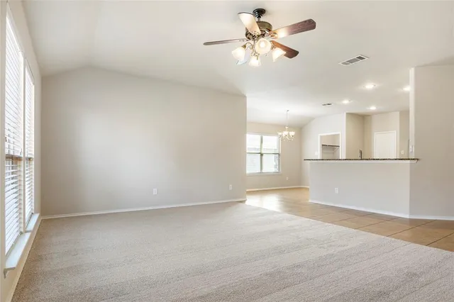 an empty room with chandelier fan and windows