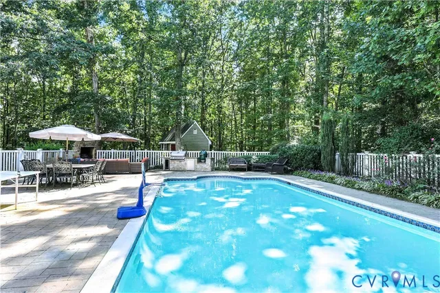 a view of a swimming pool with lawn chairs under an umbrella