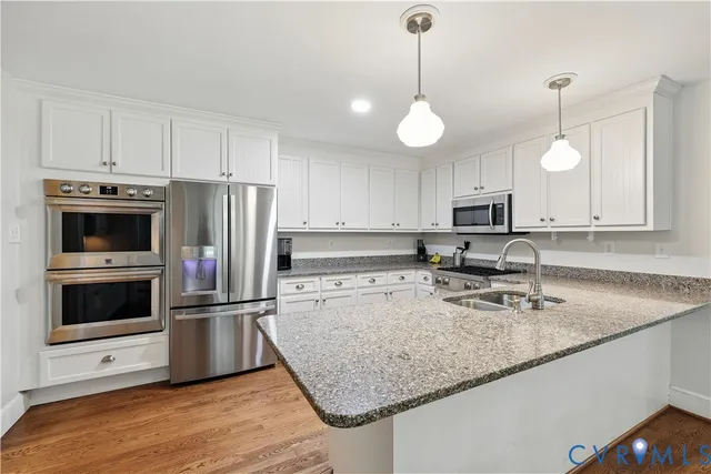 a kitchen with stainless steel appliances granite countertop a sink a stove a refrigerator and cabinets