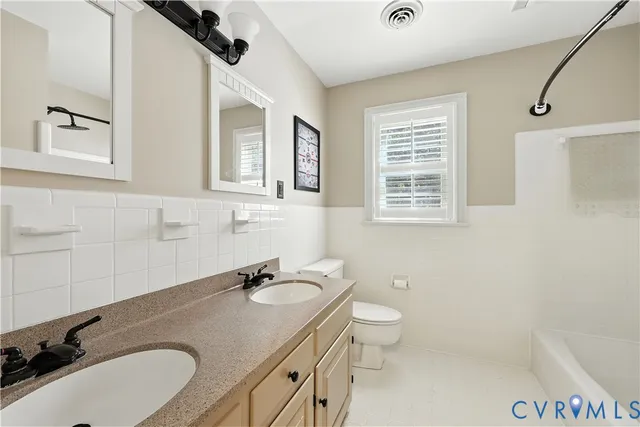 a bathroom with a granite countertop sink toilet and mirror