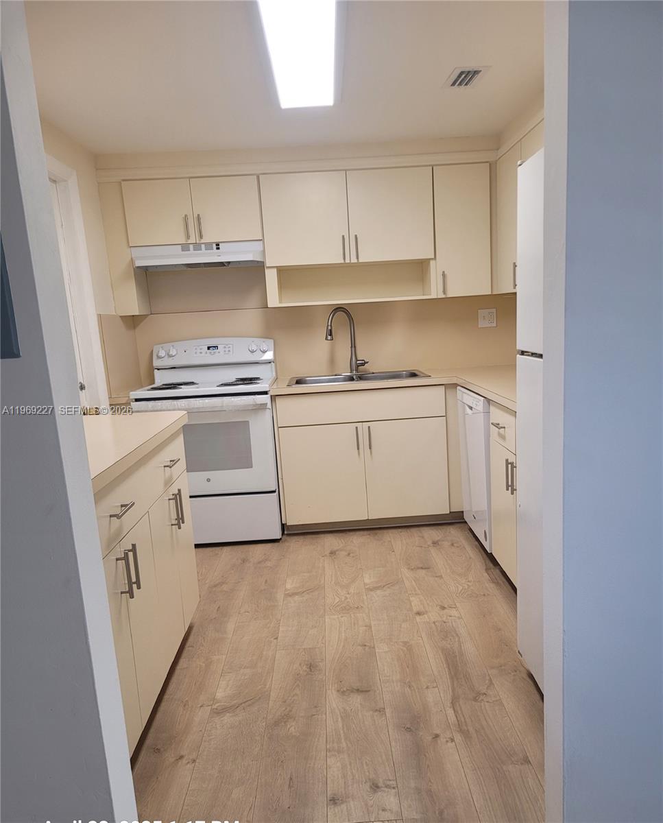 14140 Southwest 84th Street, Unit 301H Miami, FL 33183 - Photo 19 of 39 a kitchen with granite countertop white cabinets and white appliances