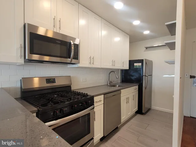a kitchen with stainless steel appliances a stove a microwave a sink and cabinets