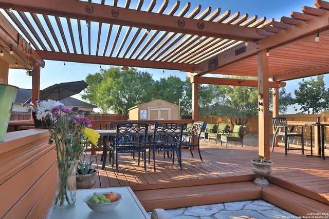 a view of a patio with table and chairs potted plants with wooden floor and fence