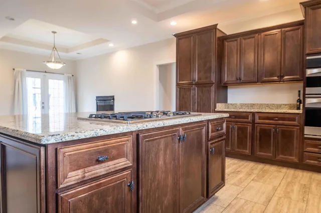 a kitchen with stainless steel appliances granite countertop wooden cabinets stove top oven and sink