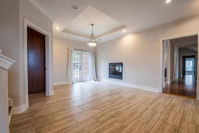 a view of an empty room with window and wooden floor