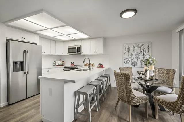 a kitchen with stainless steel appliances a table chairs refrigerator and cabinets