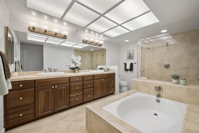a spacious bathroom with a tub double sink and mirror
