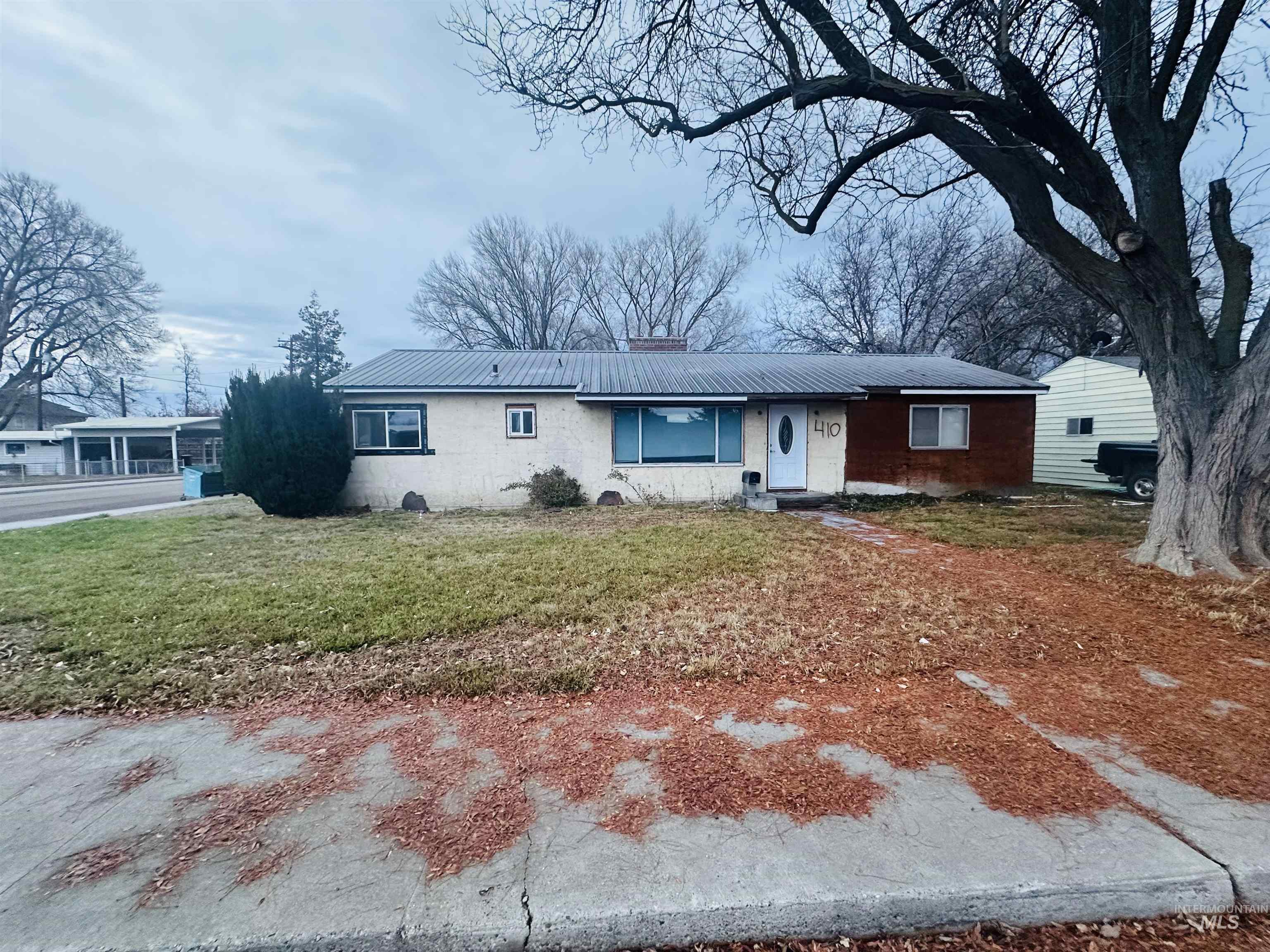 Single story home with a metal roof, a front yard, and a chimney