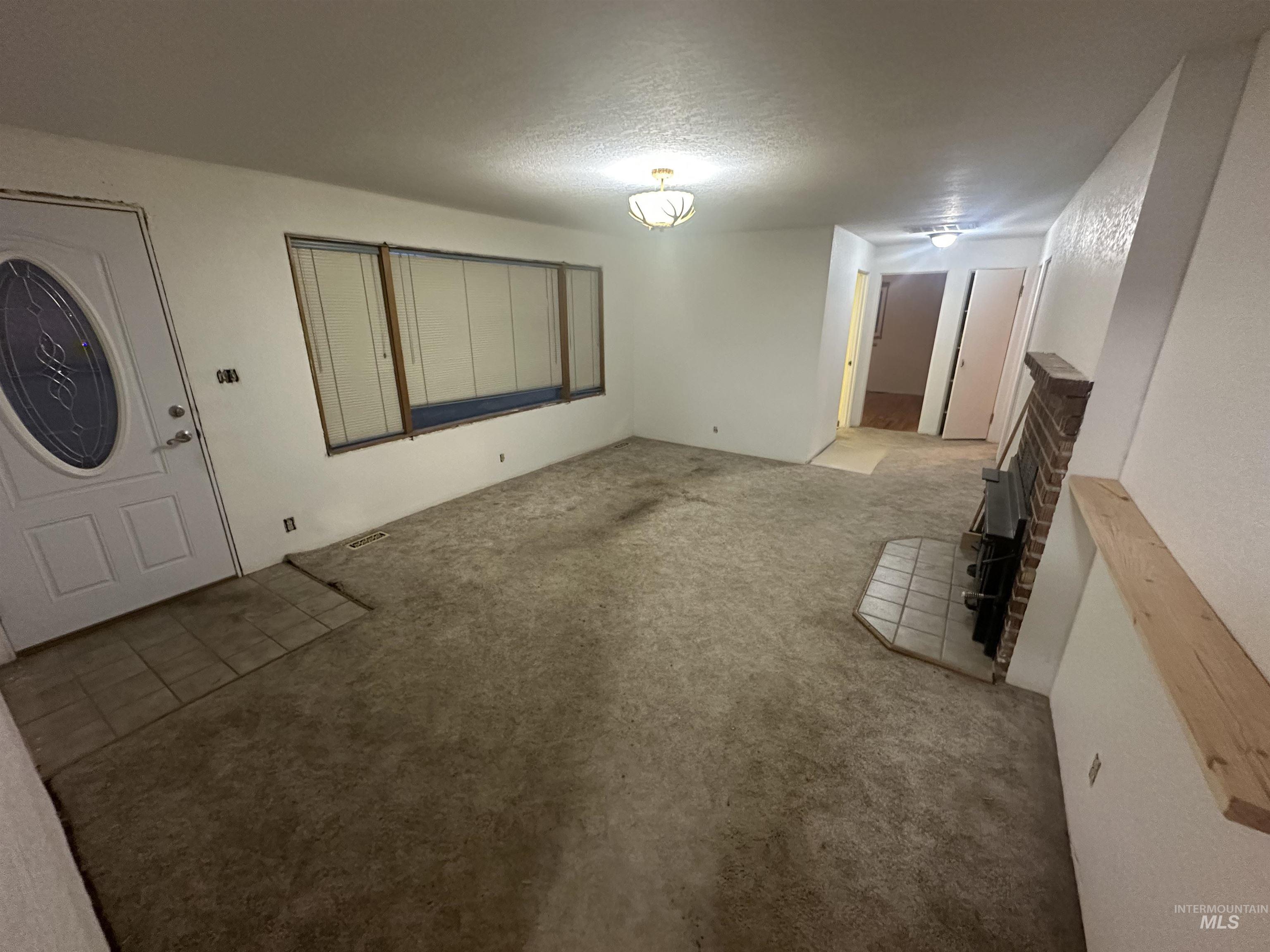 410 South Yakima Street Vale, OR 97918 - Photo 7 of 29 Unfurnished living room featuring carpet floors and a textured ceiling
