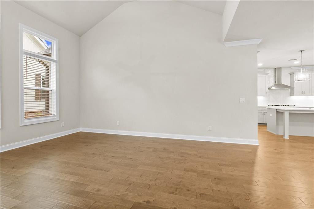 579 Pearl Street Cumming, GA 30040 - Photo 6 of 30 a view of empty room with wooden floor and kitchen view