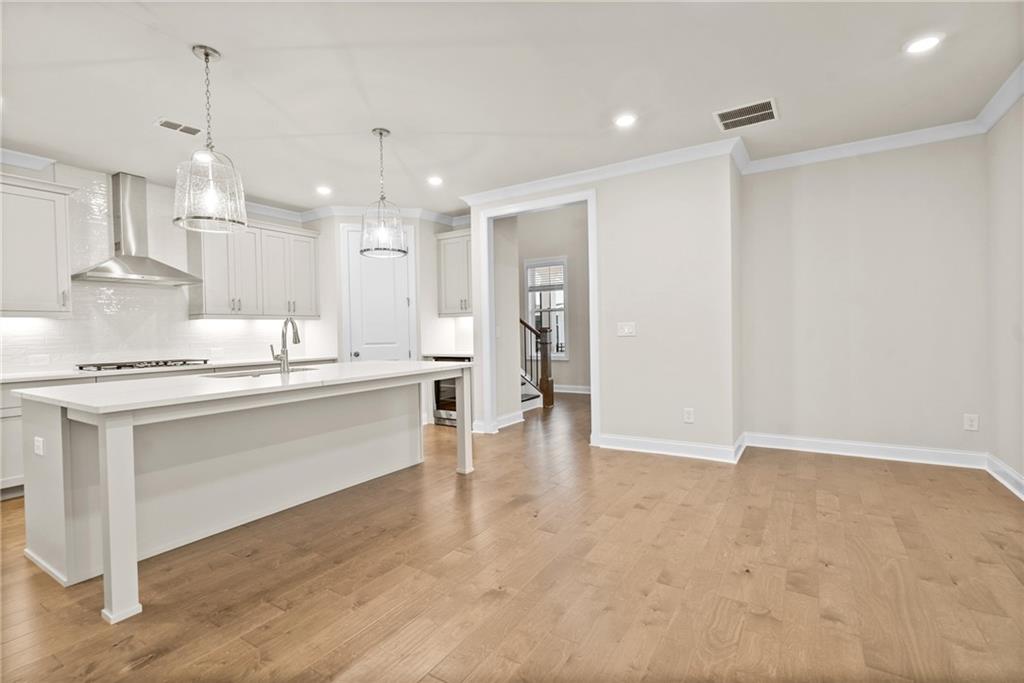 579 Pearl Street Cumming, GA 30040 - Photo 9 of 30 a large white kitchen with a refrigerator a sink dishwasher a stove and a dining table with wooden floor