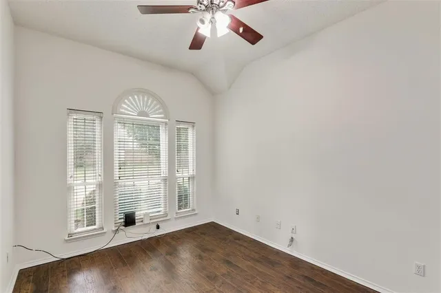 an empty room with wooden floor chandelier and windows