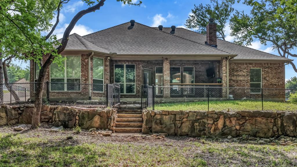 203 Mockingbird Lane Aledo, TX 76008 - Photo 34 of 37 Brick exterior featuring a covered patio, tiered retaining walls, a fenced yard, and multi-pane windows