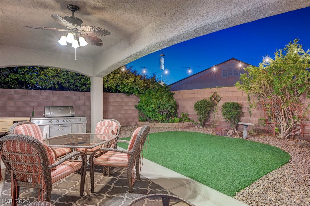1604 Cattle Ranch Place Henderson, NV 89002 - Photo 91 of 99 An inviting covered patio with a ceiling fan overlooks a landscaped private yard with artificial turf and a built-in barbecue.