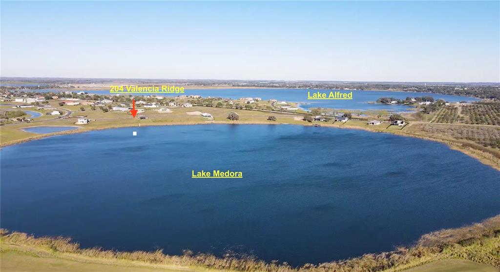 an aerial view of ocean and residential houses with outdoor space