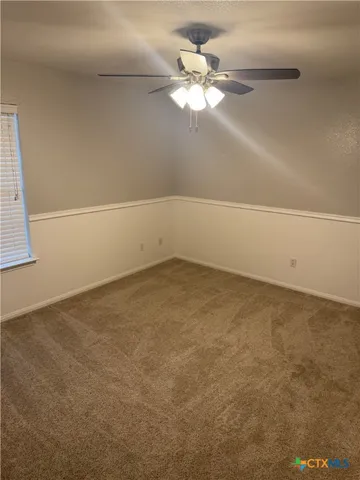 an empty room with a chandelier fan and windows