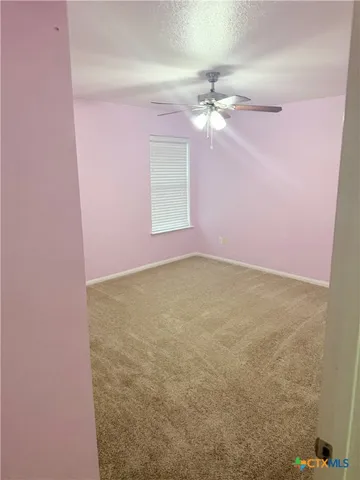 en empty room with chandelier fan and fire place