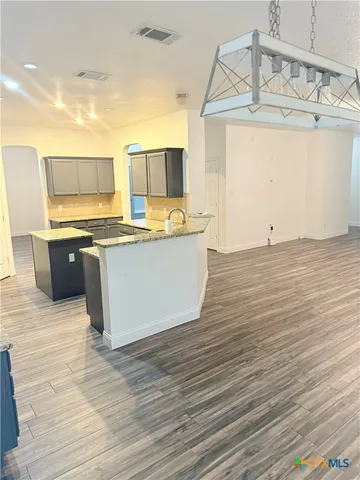 a living room with stainless steel appliances kitchen island granite countertop a sink and cabinets
