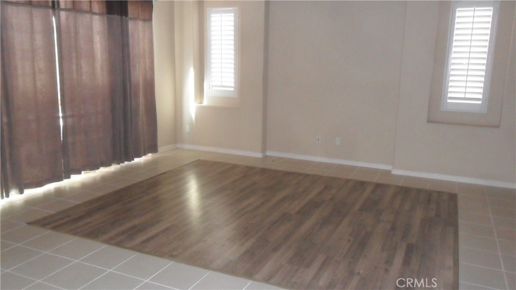 36277 Waxen Road Lake Elsinore, CA 92532 - Photo 5 of 27 an empty room with wooden floor and windows with curtains