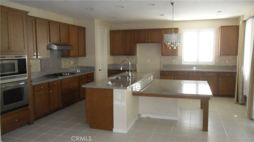 36277 Waxen Road Lake Elsinore, CA 92532 - Photo 7 of 27 a kitchen with kitchen island granite countertop stainless steel appliances a sink stove and refrigerator