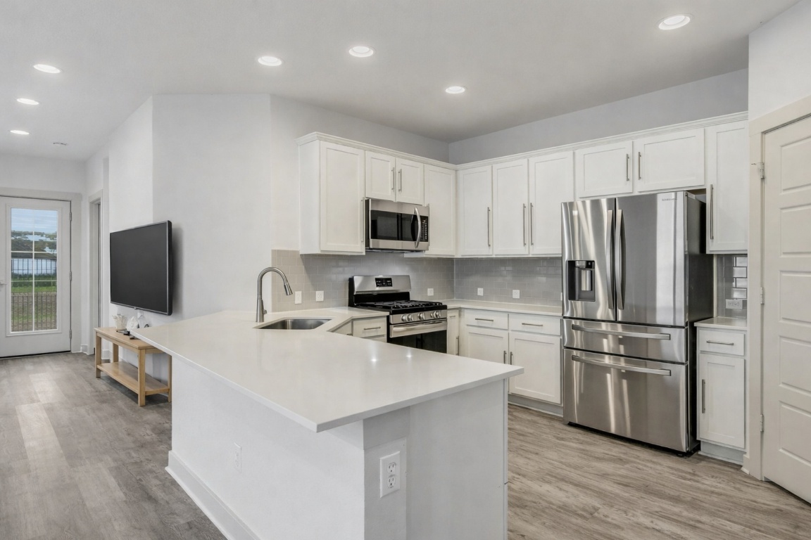 5125 Vanner Path Georgetown, TX 78626 - Photo 11 of 27 Kitchen featuring appliances with stainless steel finishes, white cabinetry, recessed lighting, a peninsula, and light wood-style flooring. Digitally Staged.