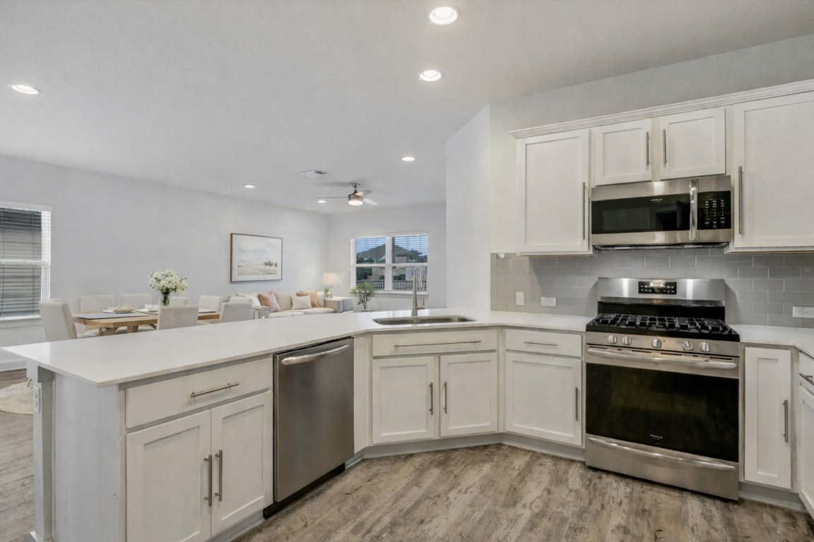 5125 Vanner Path Georgetown, TX 78626 - Photo 27 of 27 Kitchen featuring stainless steel appliances, white cabinets, open floor plan, light wood-type flooring, and recessed lighting. Digitally Staged.