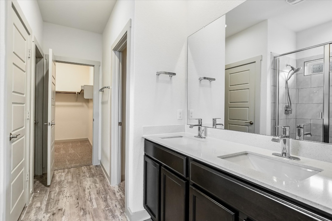 5125 Vanner Path Georgetown, TX 78626 - Photo 15 of 27 Bathroom with a walk in closet, double vanity, a shower stall, and light wood-style flooring