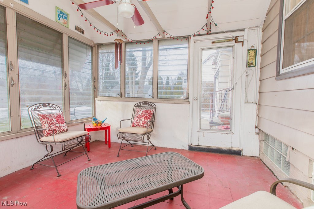 1528 Oakmount Road South Euclid, OH 44121 - Photo 23 of 24 Screen porch with party lights and wood flooring painted red along with a ceiling fan with red blades.