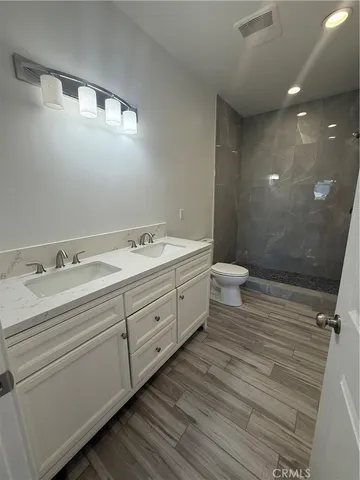 a bathroom with a double vanity sink a toilet and a mirror