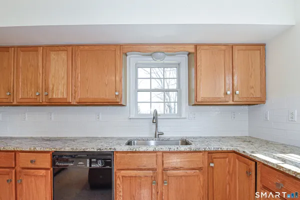 a kitchen with granite countertop stainless steel appliances white cabinets sink and a granite counter top