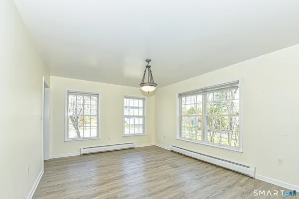 a view of an empty room with wooden floor and windows