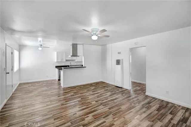 a view of kitchen and empty room with wooden floor