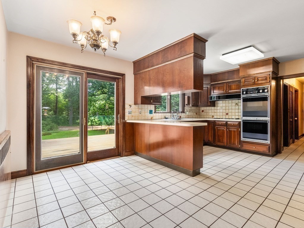 59 Spywood Road Sherborn, MA 01770 - Photo 10 of 40 a kitchen with stainless steel appliances kitchen island granite countertop a refrigerator a sink dishwasher and white cabinets with wooden floor
