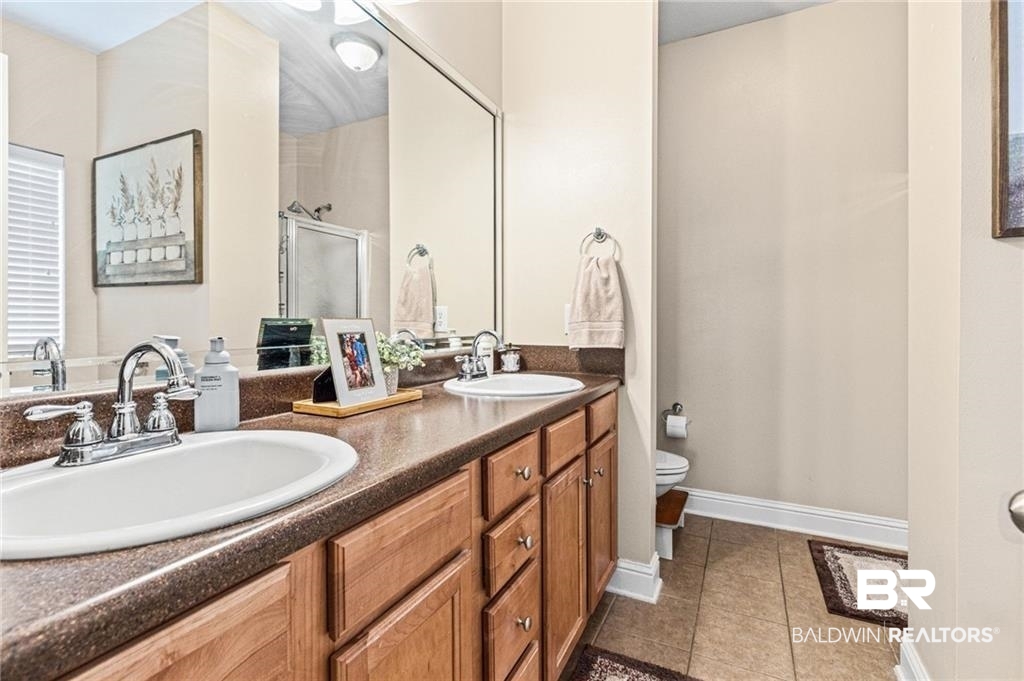 2570 Pecan Pointe Drive Semmes, AL 36575 - Photo 11 of 22 Bathroom featuring double vanity, dark tile patterned flooring, and a stall shower