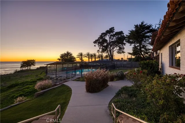 a view of an empty room with wooden floor and fan