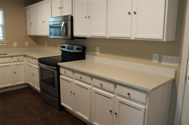 a bed sitting in a kitchen with cabinets and wooden floor