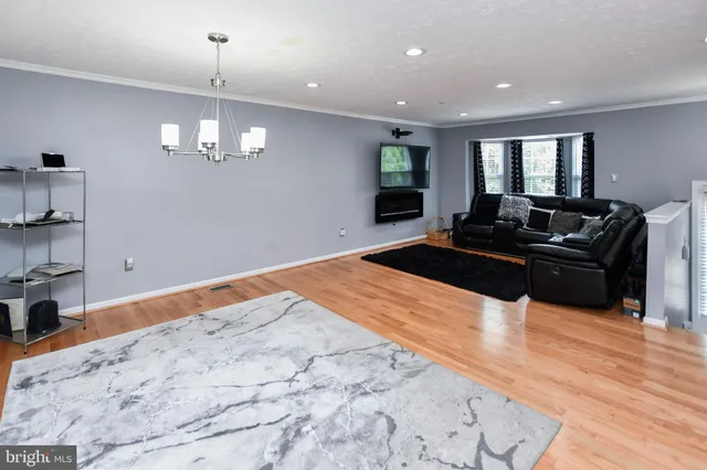 a large bedroom with wooden floor and chandelier