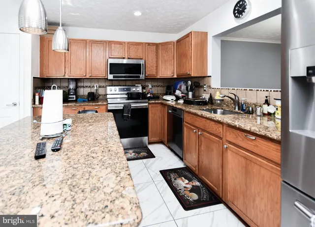 a kitchen with stainless steel appliances kitchen island granite countertop a sink dishwasher stove top oven and cabinets