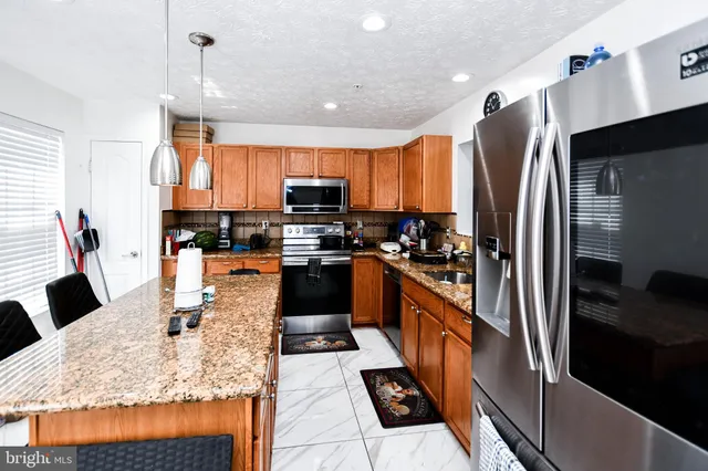 a kitchen with stainless steel appliances kitchen island granite countertop a refrigerator a stove a sink a microwave and island