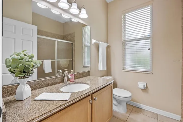 a bathroom with a granite countertop sink a toilet and a mirror