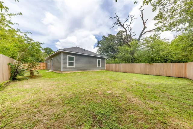 a view of a yard in front of a house with a large tree