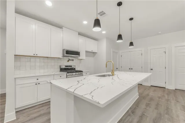 a kitchen with a stove a sink a microwave and cabinets