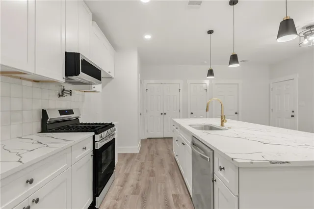 a kitchen with a sink stainless steel appliances and white cabinets