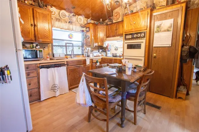 a dining hall with stainless steel appliances a dining table and chairs with wooden floor