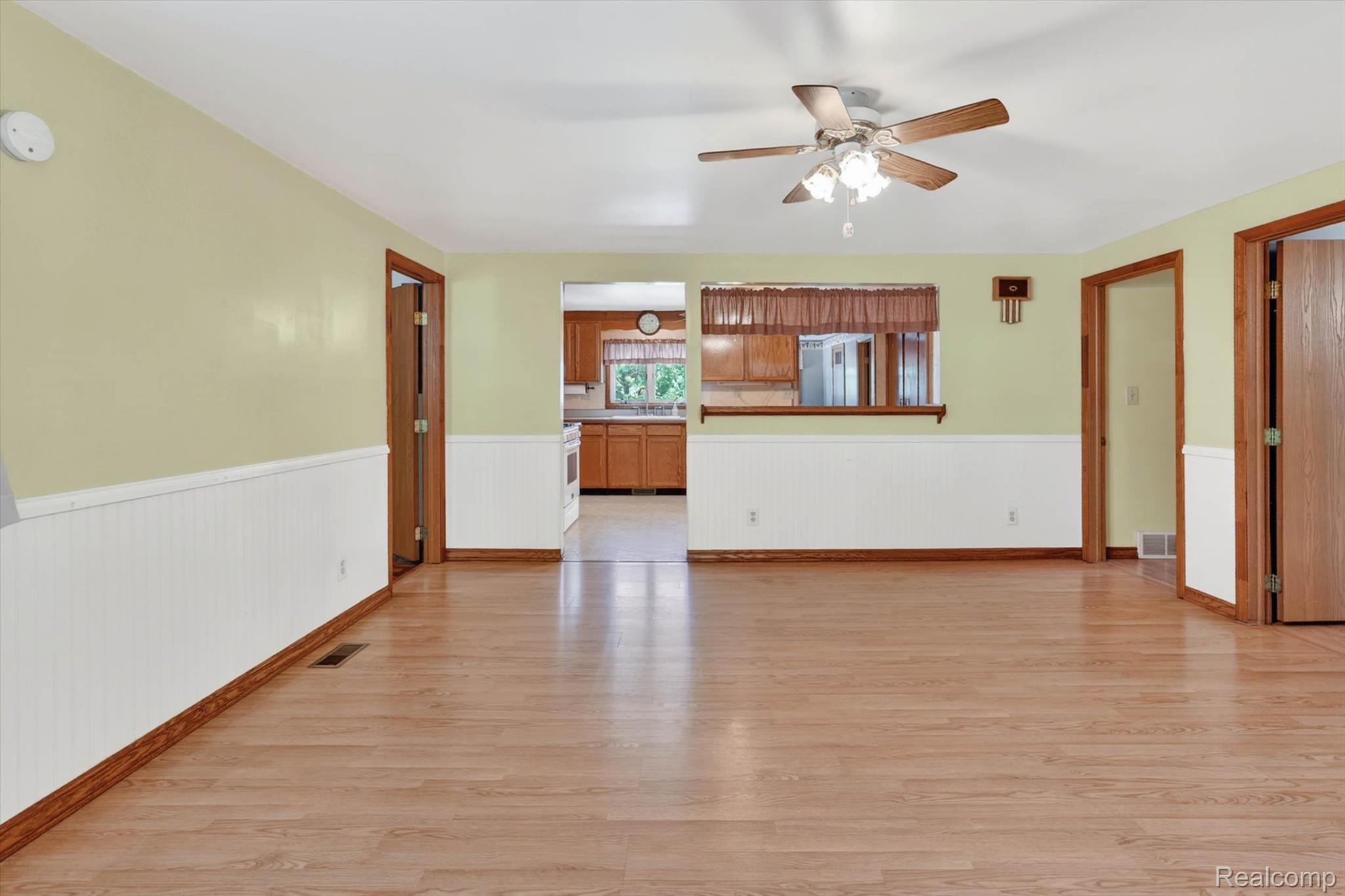7974 West Gilford Road Reese, MI 48757 - Photo 9 of 36 Unfurnished living room with light wood-style floors, a ceiling fan, and wainscoting